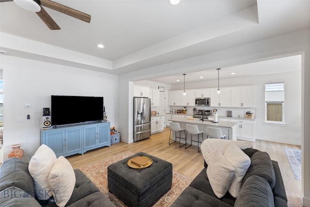 1502 Cyril Way, Belgrade, MT 59714 - living area featuring a ceiling fan, light wood-type flooring, recessed lighting, baseboards, and a tray ceiling