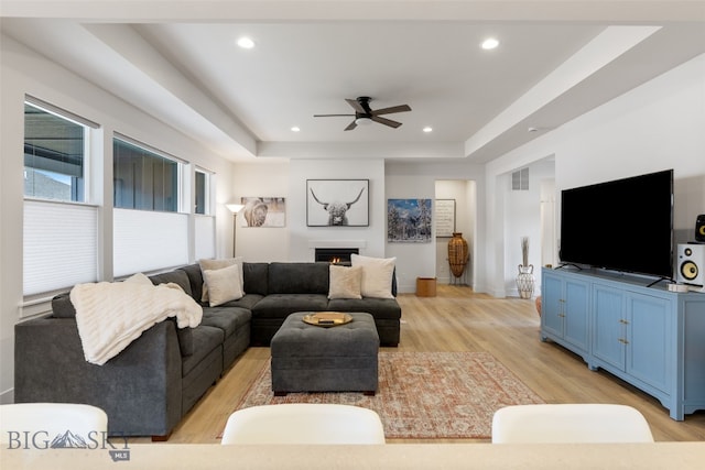 1502 Cyril Way, Belgrade, MT 59714 - living area with ceiling fan, light wood finished floors, a tray ceiling, recessed lighting, and a lit fireplace
