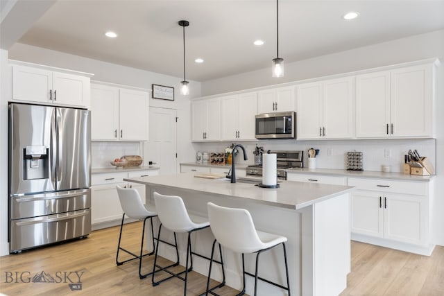 1502 Cyril Way, Belgrade, MT 59714 - kitchen featuring stainless steel appliances, backsplash, white cabinetry, a kitchen bar, and recessed lighting