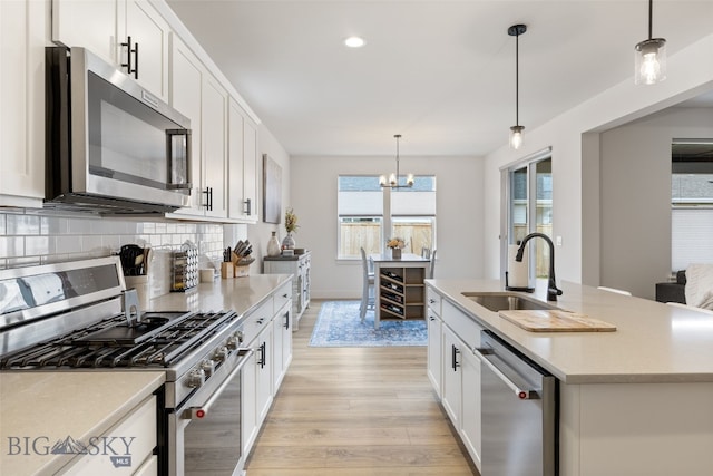1502 Cyril Way, Belgrade, MT 59714 - kitchen featuring appliances with stainless steel finishes, a sink, light wood-type flooring, a chandelier, and tasteful backsplash