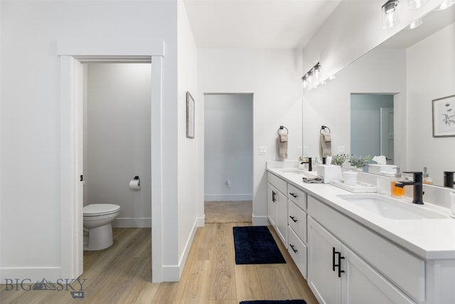 1502 Cyril Way, Belgrade, MT 59714 - bathroom featuring double vanity, wood finished floors, toilet, and baseboards