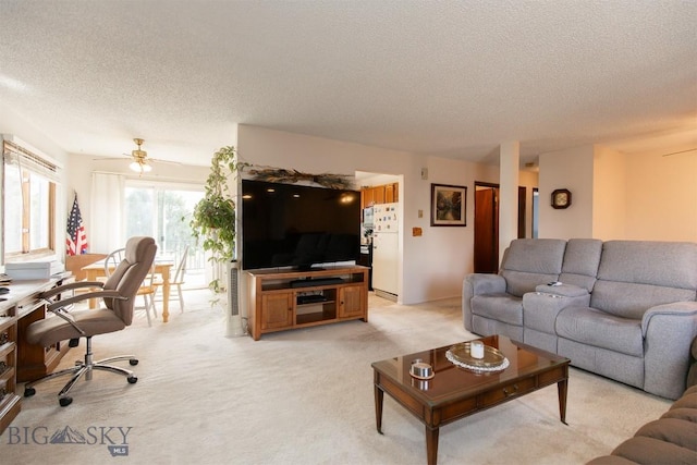 living room with a textured ceiling, ceiling fan, and light colored carpet