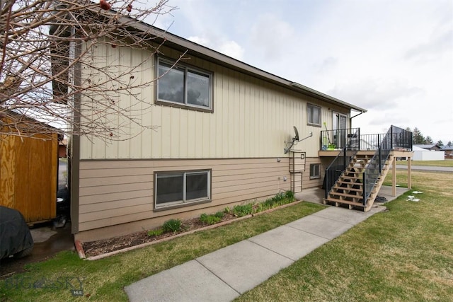 view of home's exterior featuring a lawn, stairway, and a deck