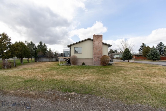 view of side of home featuring a lawn and a chimney