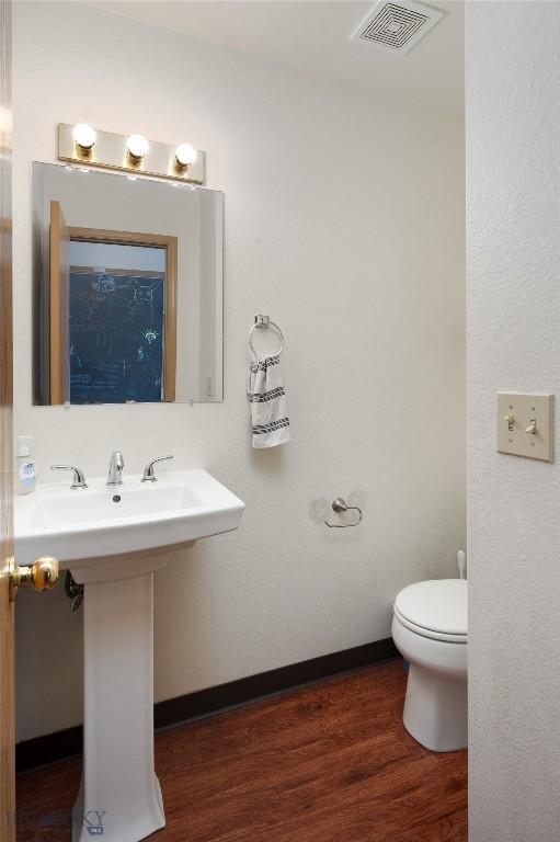 1719 W Kagy, Bozeman, MT 59715 - bathroom with a sink, toilet, wood finished floors, visible vents, and baseboards