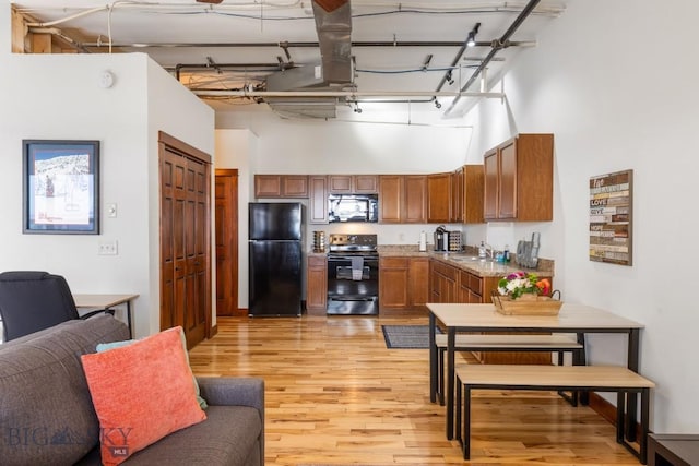 67 Village Dr Unit 4A, Belgrade, MT 59714 - kitchen featuring black appliances, a towering ceiling, light wood-type flooring, and open floor plan