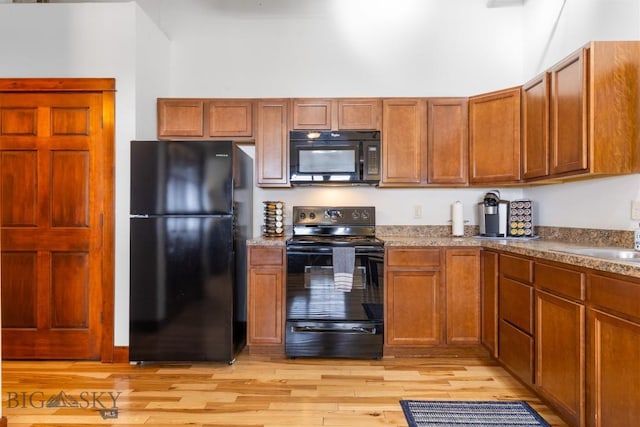 67 Village Dr Unit 4A, Belgrade, MT 59714 - kitchen featuring black appliances, light wood-type flooring, brown cabinetry, and a sink