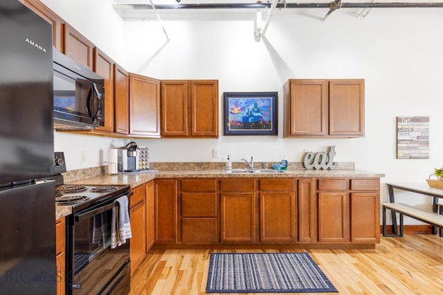 67 Village Dr Unit 4A, Belgrade, MT 59714 - kitchen featuring black appliances, a sink, light wood-style floors, and brown cabinets