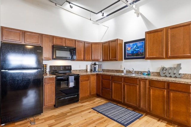 67 Village Dr Unit 4A, Belgrade, MT 59714 - kitchen with black appliances, a towering ceiling, light wood-type flooring, a sink, and track lighting