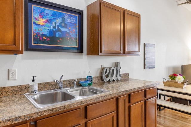67 Village Dr Unit 4A, Belgrade, MT 59714 - kitchen featuring a sink, brown cabinetry, and wood finished floors
