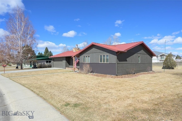 ranch-style house featuring driveway, a front yard, an attached garage, and metal roof