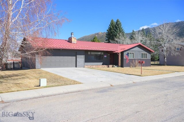 single story home featuring fence, an attached garage, metal roof, driveway, and a front yard