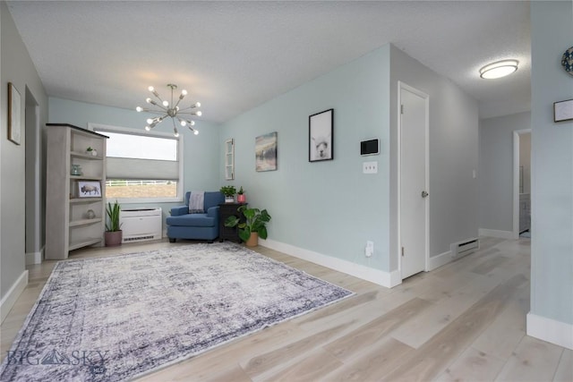 living area with a textured ceiling, light wood-style floors, baseboards, and an inviting chandelier