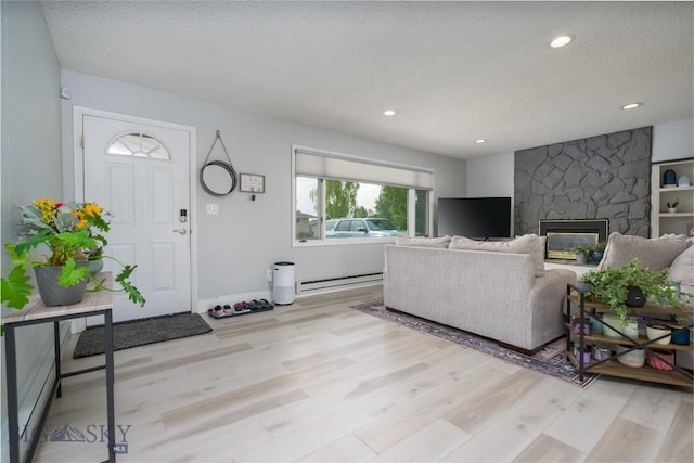 living room featuring light wood-type flooring, recessed lighting, a stone fireplace, and a textured ceiling