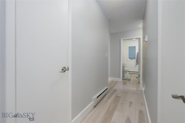 hall with baseboards, a textured ceiling, a baseboard heating unit, and light wood-type flooring