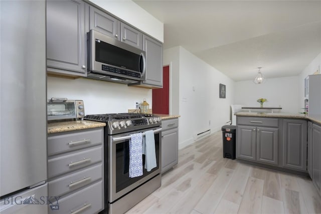 kitchen with light stone countertops, gray cabinetry, light wood-type flooring, stainless steel appliances, and baseboards