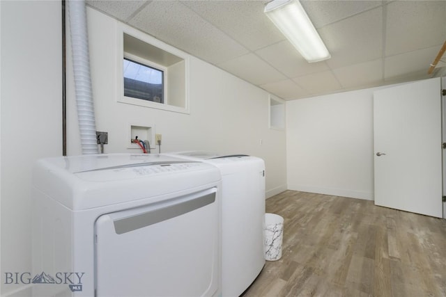 laundry area featuring washer and clothes dryer, light wood-type flooring, laundry area, and baseboards