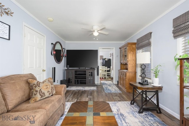 living area featuring crown molding, baseboards, a ceiling fan, and dark wood finished floors