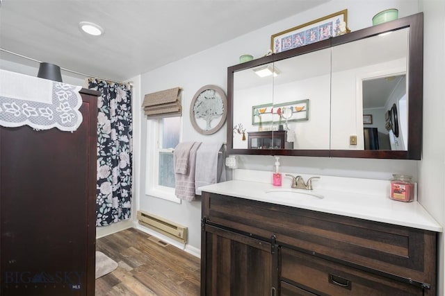bathroom with vanity, curtained shower, a baseboard heating unit, and wood finished floors