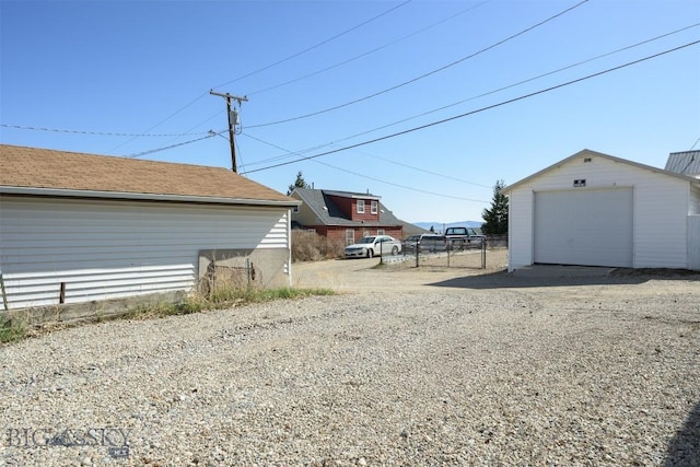 view of yard with a garage, fence, an outbuilding, and gravel driveway