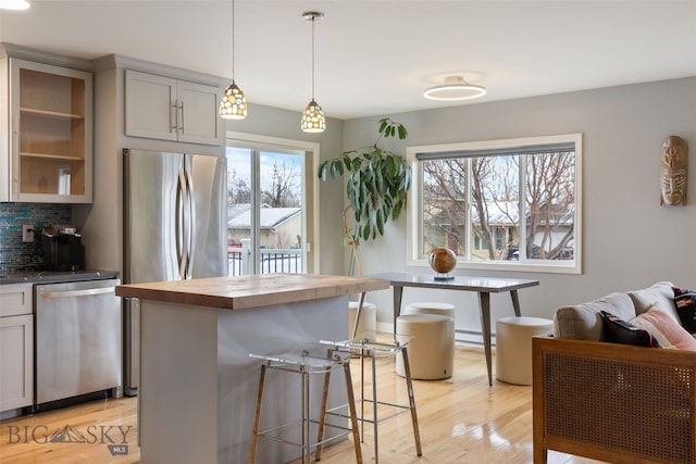 211 N Yellowstone Ave, Bozeman, MT 59718 - kitchen featuring appliances with stainless steel finishes, wood counters, light wood finished floors, a breakfast bar, and a baseboard heating unit