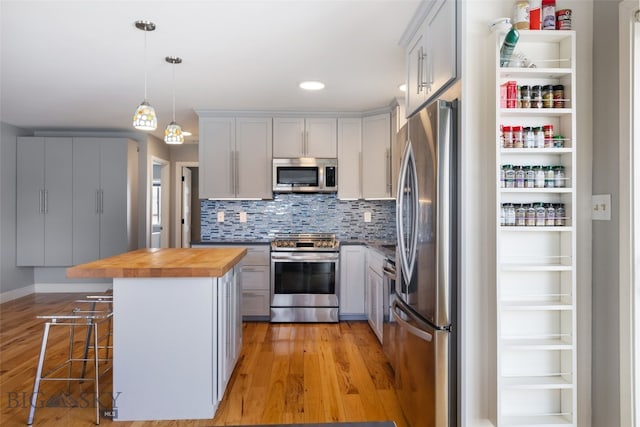 211 N Yellowstone Ave, Bozeman, MT 59718 - kitchen featuring stainless steel appliances, butcher block counters, light wood-style floors, a breakfast bar area, and backsplash