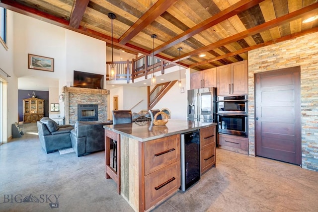 251 Fawn Mdw, Manhattan, MT 59741 - kitchen with beverage cooler, light carpet, a stone fireplace, a kitchen island, and a high ceiling