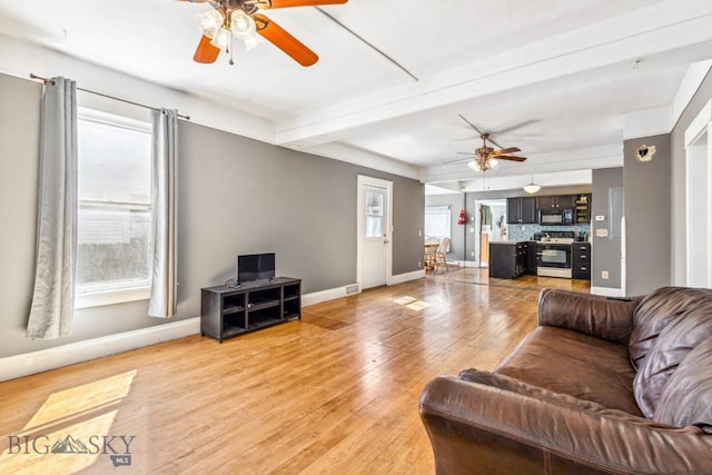 living area featuring baseboards, beamed ceiling, ceiling fan, and light wood-type flooring