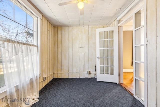 spare room with carpet floors, wood walls, and ceiling fan