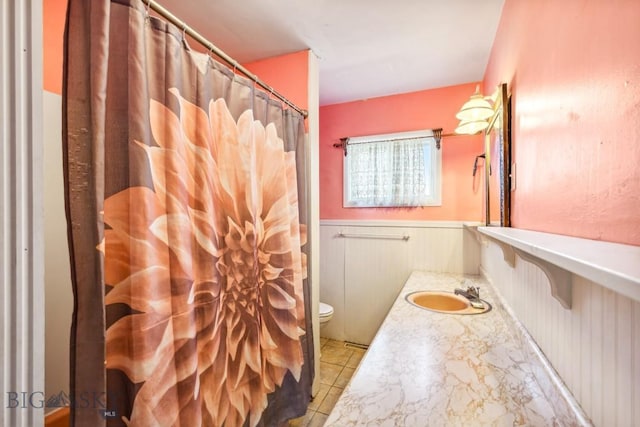 bathroom featuring tile patterned floors, wainscoting, toilet, and vanity