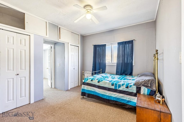 carpeted bedroom featuring multiple closets and ceiling fan