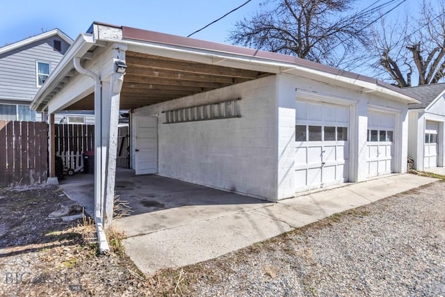 view of side of property featuring a detached garage, fence, and concrete block siding