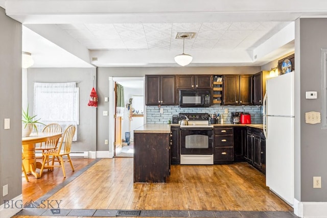 kitchen featuring light countertops, freestanding refrigerator, black microwave, electric range oven, and decorative backsplash