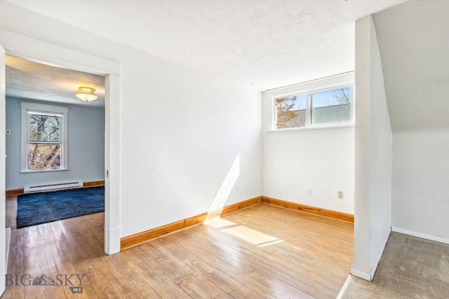 spare room with a baseboard radiator, hardwood / wood-style flooring, baseboards, and a textured ceiling