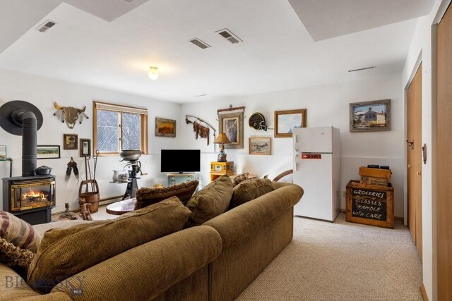 490 Secretariat Cir, Belgrade, MT 59714 - living area featuring light carpet, a wood stove, and visible vents