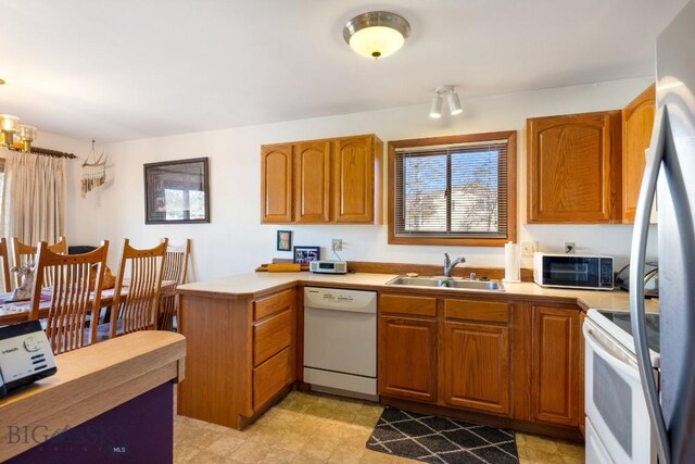 490 Secretariat Cir, Belgrade, MT 59714 - kitchen featuring white appliances, a peninsula, brown cabinets, and a sink