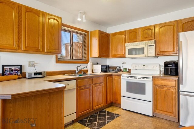 490 Secretariat Cir, Belgrade, MT 59714 - kitchen featuring white appliances, a peninsula, brown cabinetry, and a sink