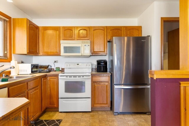 490 Secretariat Cir, Belgrade, MT 59714 - kitchen featuring white appliances, brown cabinetry, a sink, and light countertops