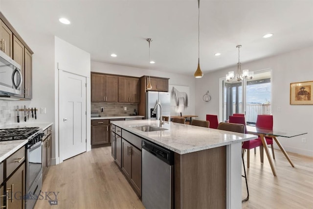 1510 Deadwood Loop, Belgrade, MT 59714 - kitchen featuring stainless steel appliances, backsplash, light wood finished floors, a kitchen bar, and recessed lighting
