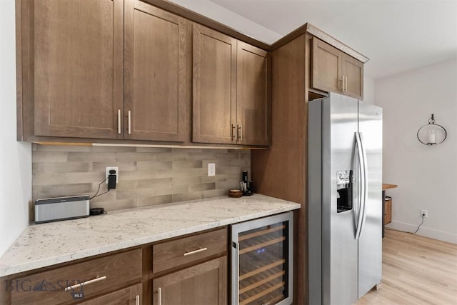 1510 Deadwood Loop, Belgrade, MT 59714 - kitchen with stainless steel refrigerator with ice dispenser, wine cooler, decorative backsplash, light stone countertops, and light wood-style floors