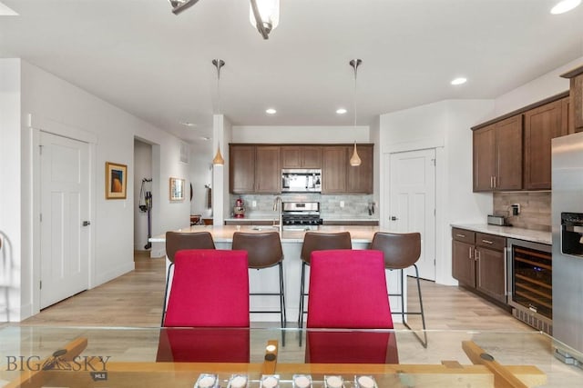 1510 Deadwood Loop, Belgrade, MT 59714 - kitchen featuring appliances with stainless steel finishes, beverage cooler, decorative backsplash, light wood-style flooring, and recessed lighting