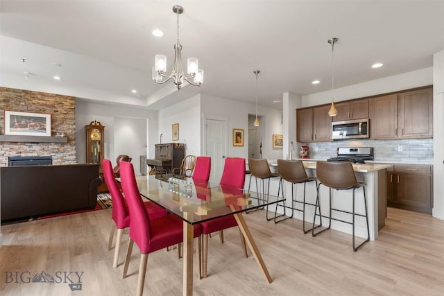 1510 Deadwood Loop, Belgrade, MT 59714 - dining room with light wood-style flooring, a chandelier, recessed lighting, and a fireplace