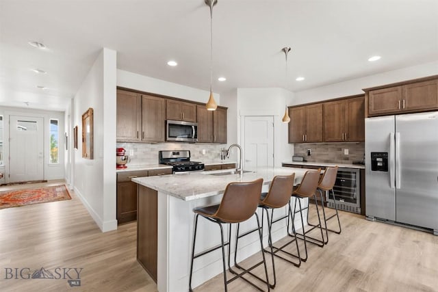 1510 Deadwood Loop, Belgrade, MT 59714 - kitchen with stainless steel appliances, beverage cooler, decorative backsplash, a kitchen bar, and light wood-type flooring