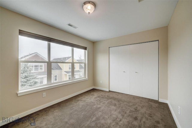unfurnished bedroom featuring a closet, carpet, visible vents, and baseboards
