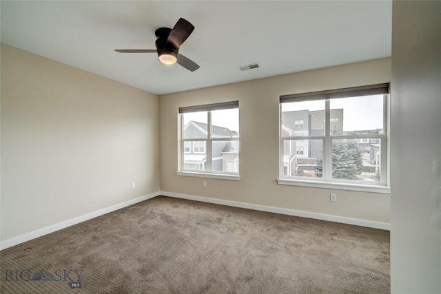 unfurnished room with carpet floors, visible vents, a ceiling fan, and baseboards