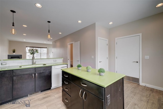 kitchen with dishwasher, light wood-style flooring, a sink, and light countertops