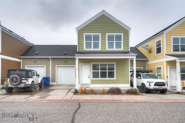 traditional-style home featuring concrete driveway, roof with shingles, and a garage