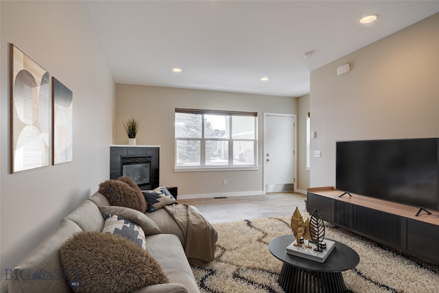 living area with baseboards, recessed lighting, light wood finished floors, and a tiled fireplace
