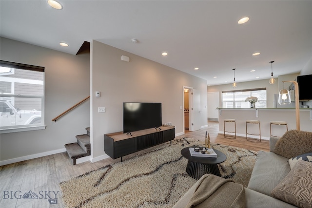 living room featuring stairway, baseboards, and light wood-type flooring