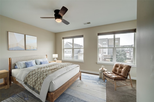 bedroom with baseboards, wood finished floors, visible vents, and ceiling fan